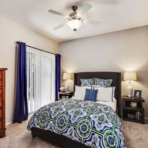 Bedroom in the model at Oakhaven with ceiling fan, sliding door, and room for dresser